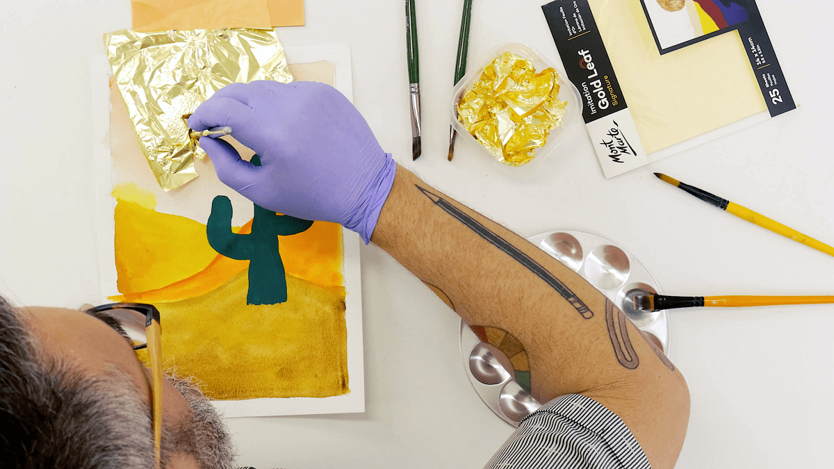 https://www.montmarte.com/cdn/shop/articles/2._Man_painting_gold_leaf_onto_an_existing_gouache_artwork_of_a_cactus_in_the_desert..png?v=1698964917